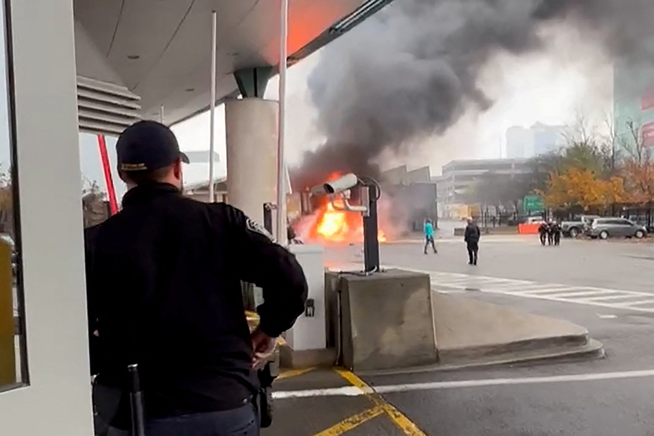 A Customs and Border Protection officer watches a car on fire at an entry point.