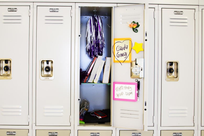 A row of lockers that would be found in a school. One is open and you can see Claudia's name written with a heart around it on the back of the door, as well as other things like books and magnets.