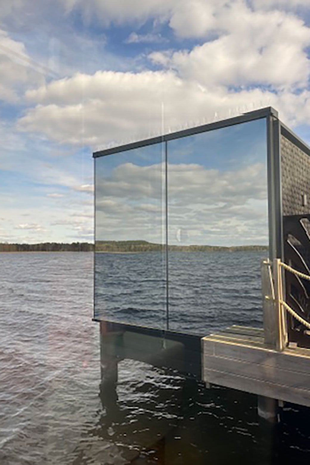 A building out over the ocean has mirrors on it.