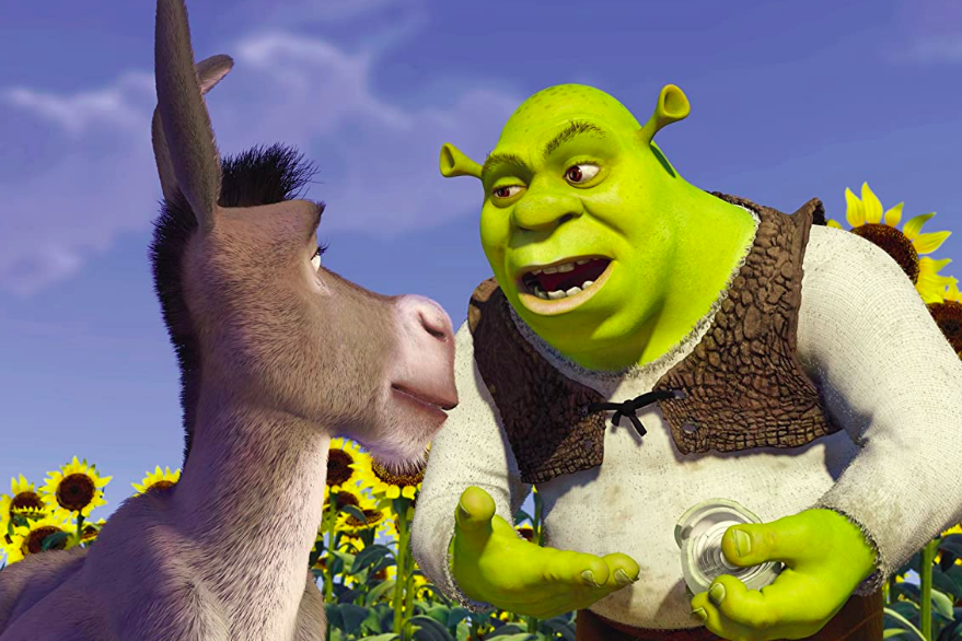 In a field of sunflowers against a bright blue sky, green-skinned Shrek shows Donkey an onion.