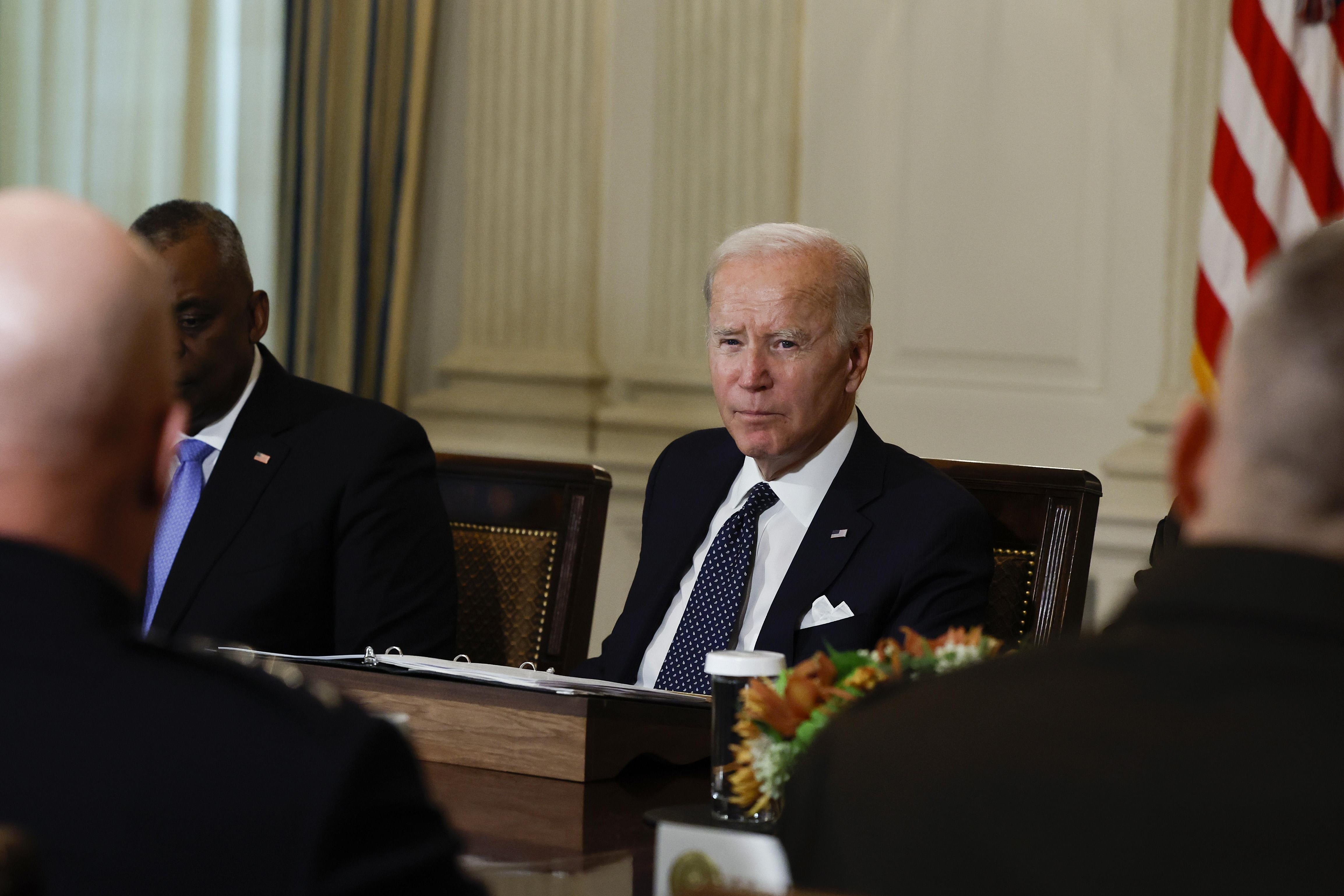 President Biden, sitting at a long table, meeting with leaders from the Department of Defense in October.