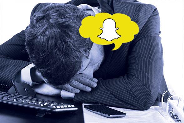 Businessman with his head on his desk having SnapChat thoughts
