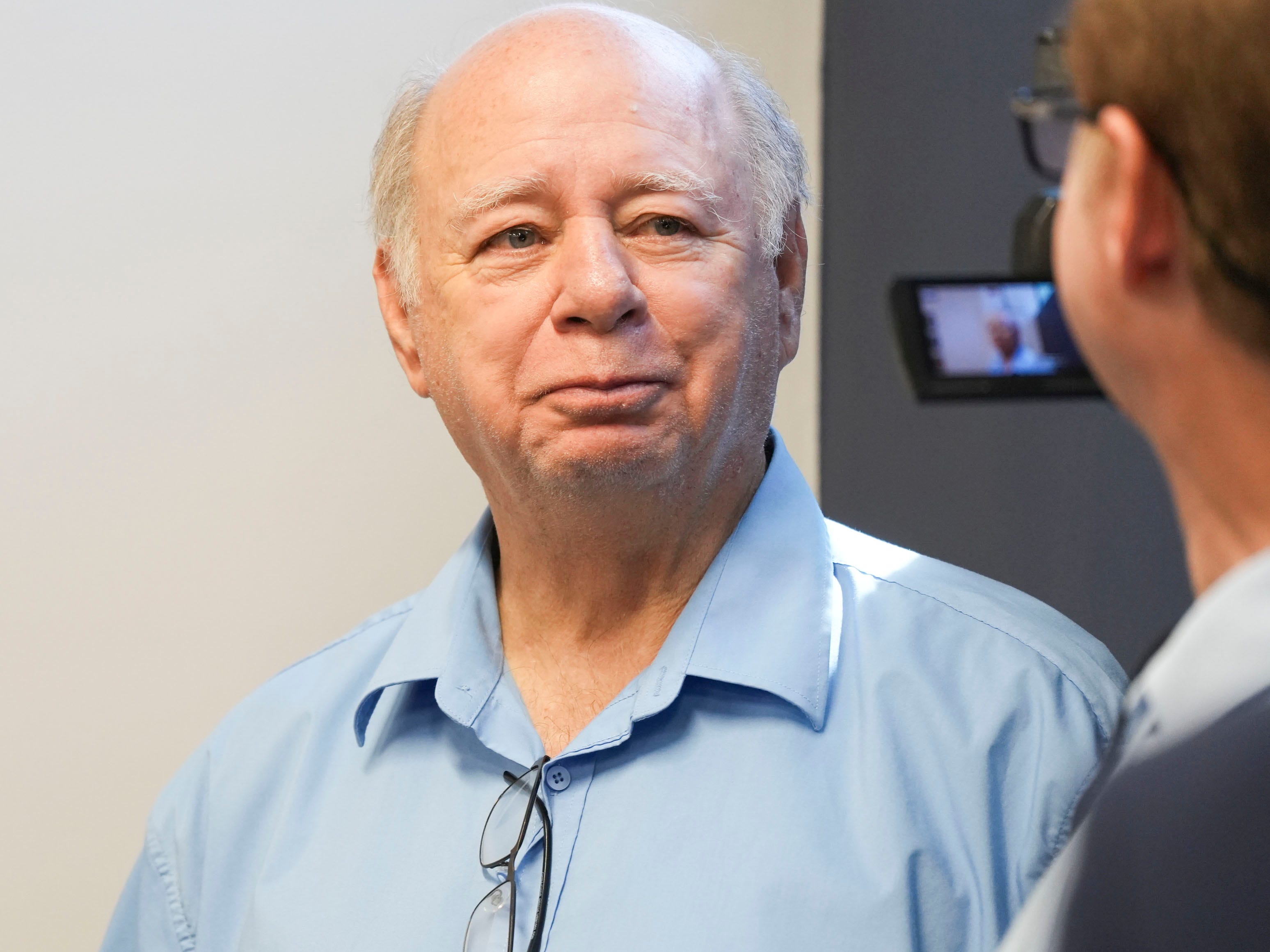 A balding older white man smiles slightly.