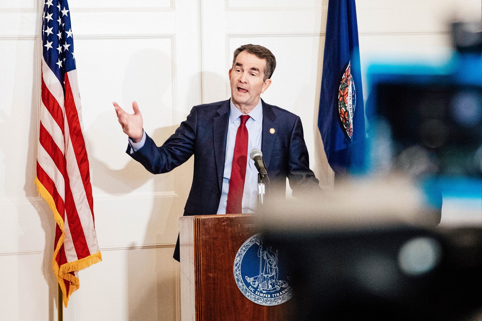 Ralph Northam at a podium, with a camera visible in the foreground.
