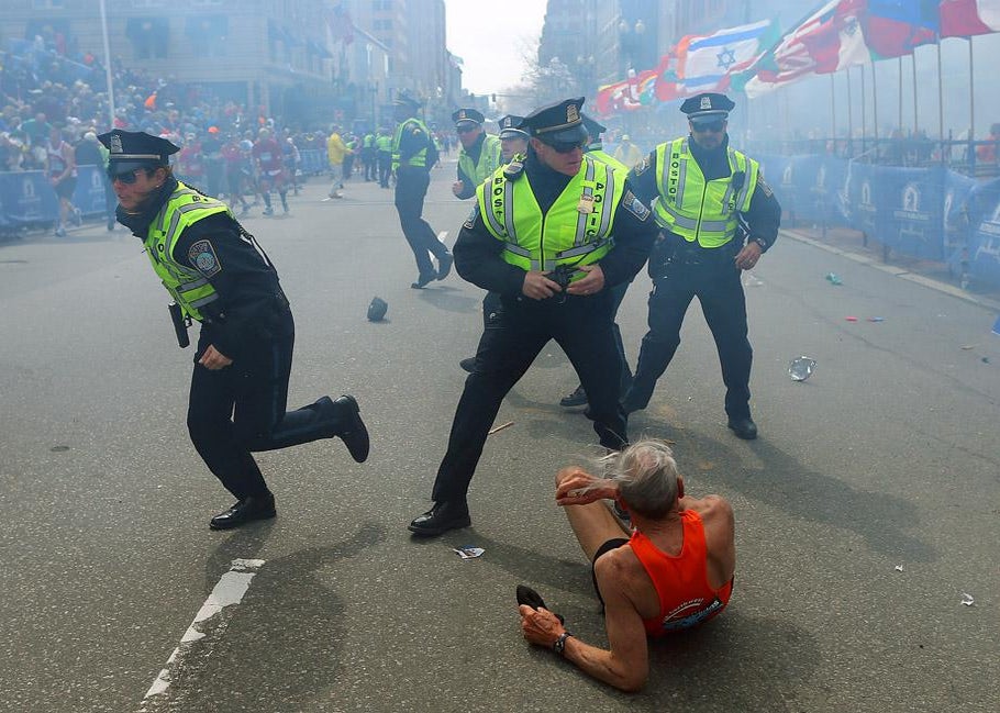 Police officers with their guns drawn hear the second explosion down the street. The first explosion knocked down a runner at the finish line of the 117th Boston Marathon.
