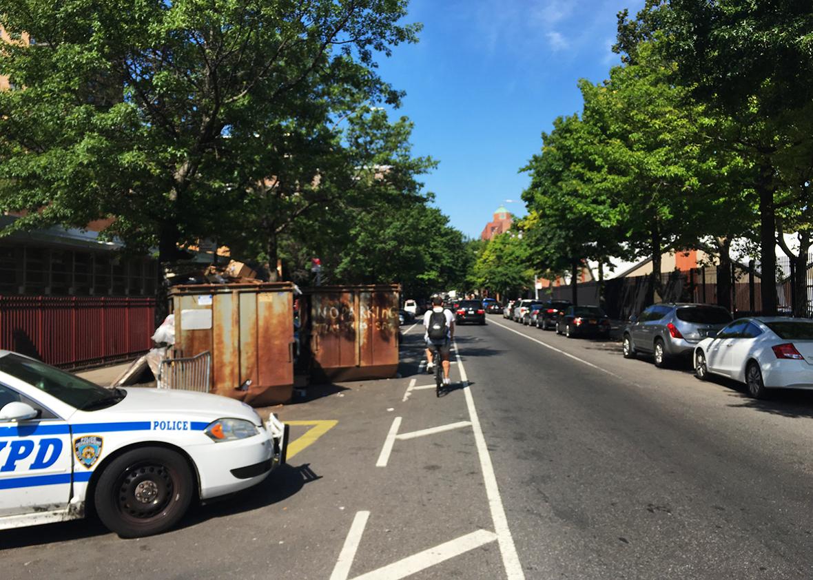 Dumpsters block a bike lane on Dekalb Avenue in front of a police precinct in Brooklyn.
