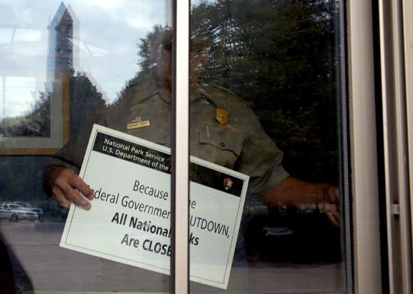U.S. Park Service employee puts a closed sign in the window of the World War II Memorial ticket office on the National Mall October 1, 2013 in Washington, DC.