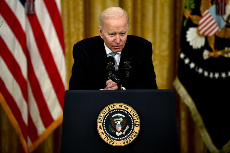 Biden crouches over a presidential podium.