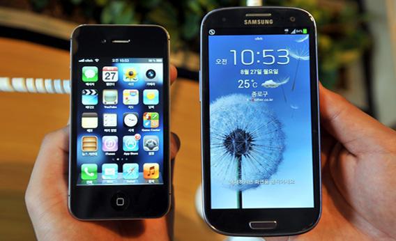 An employee shows an Apple's iPhone 4s, left, and a Samsung's Galaxy S3.