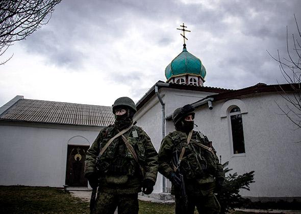 Unmarked soldiers, widely understood to be Russian, wait outside a church on a Ukrainian military base in Perevalnoye.