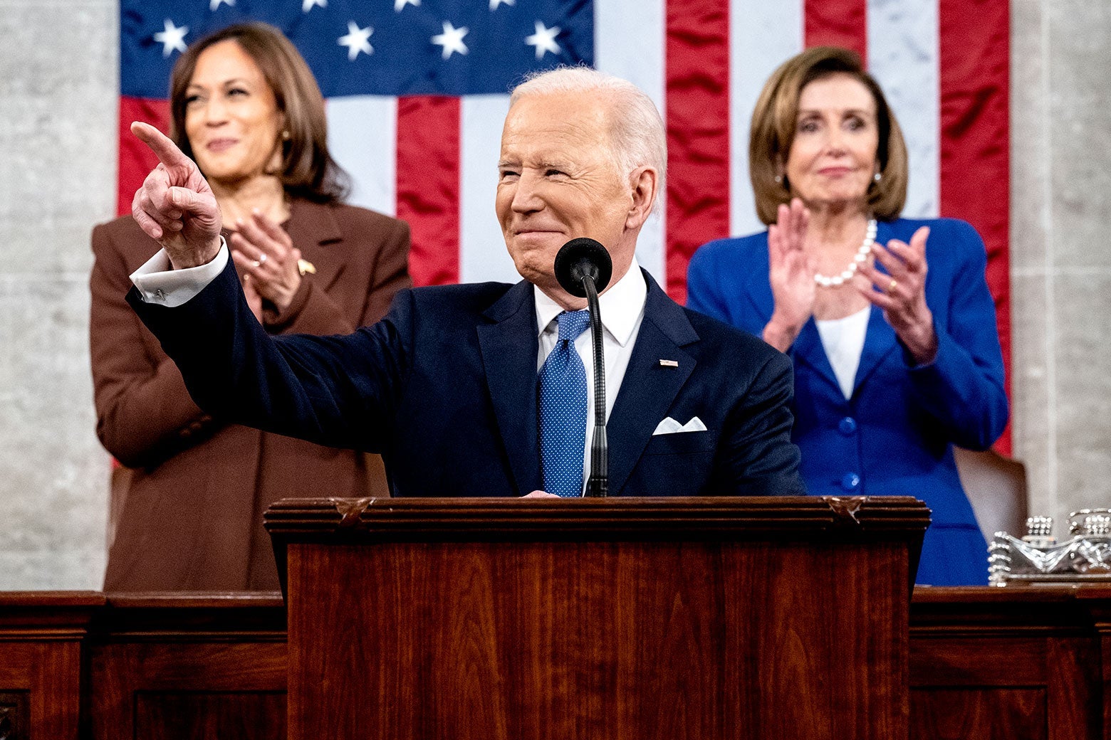 Biden smiling and pointing into the crowd during the State of the Union address as Kamala Harris and Nancy Pelosi clap behind him