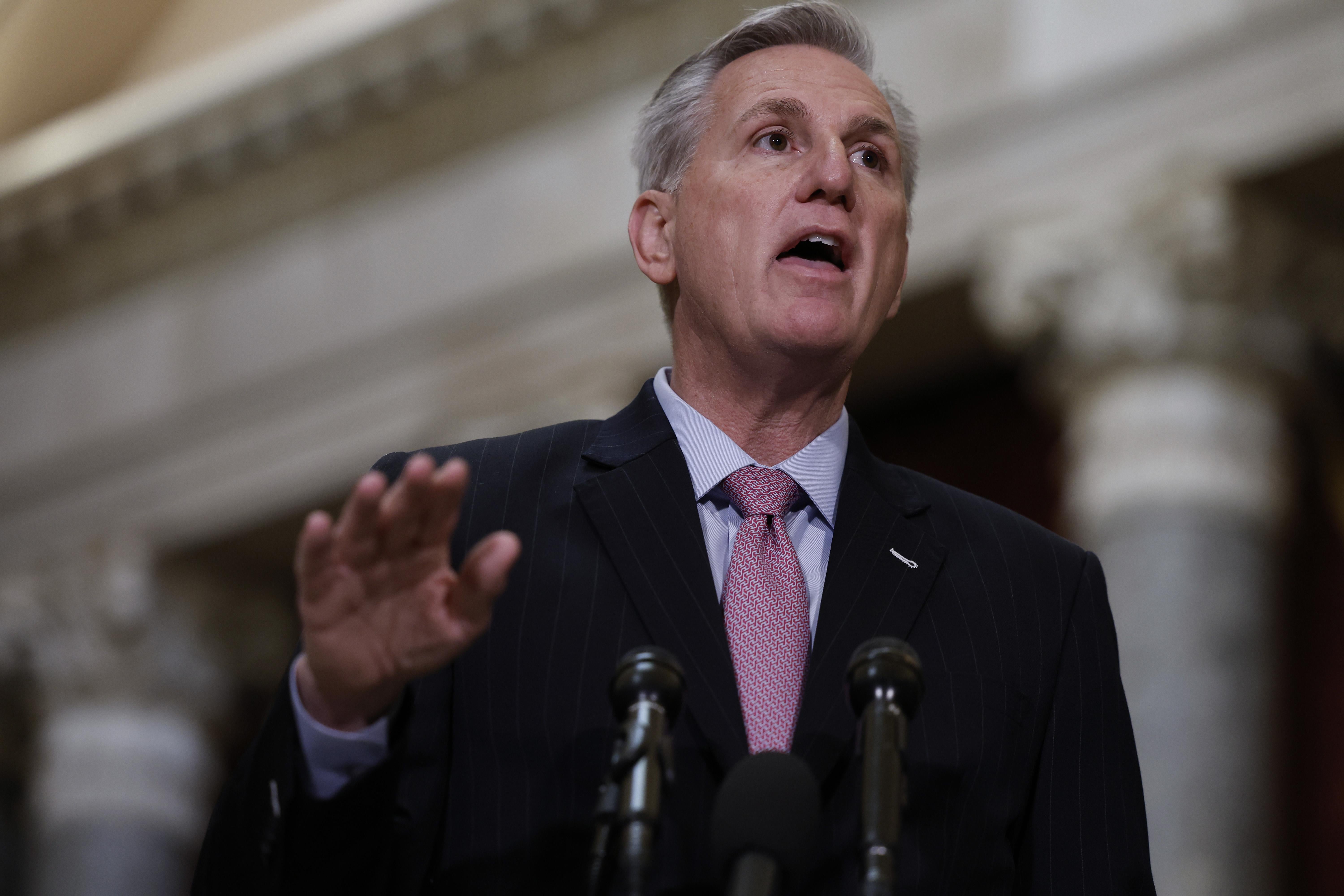 Kevin McCarthy gestures with his right hand in front of microphones.
