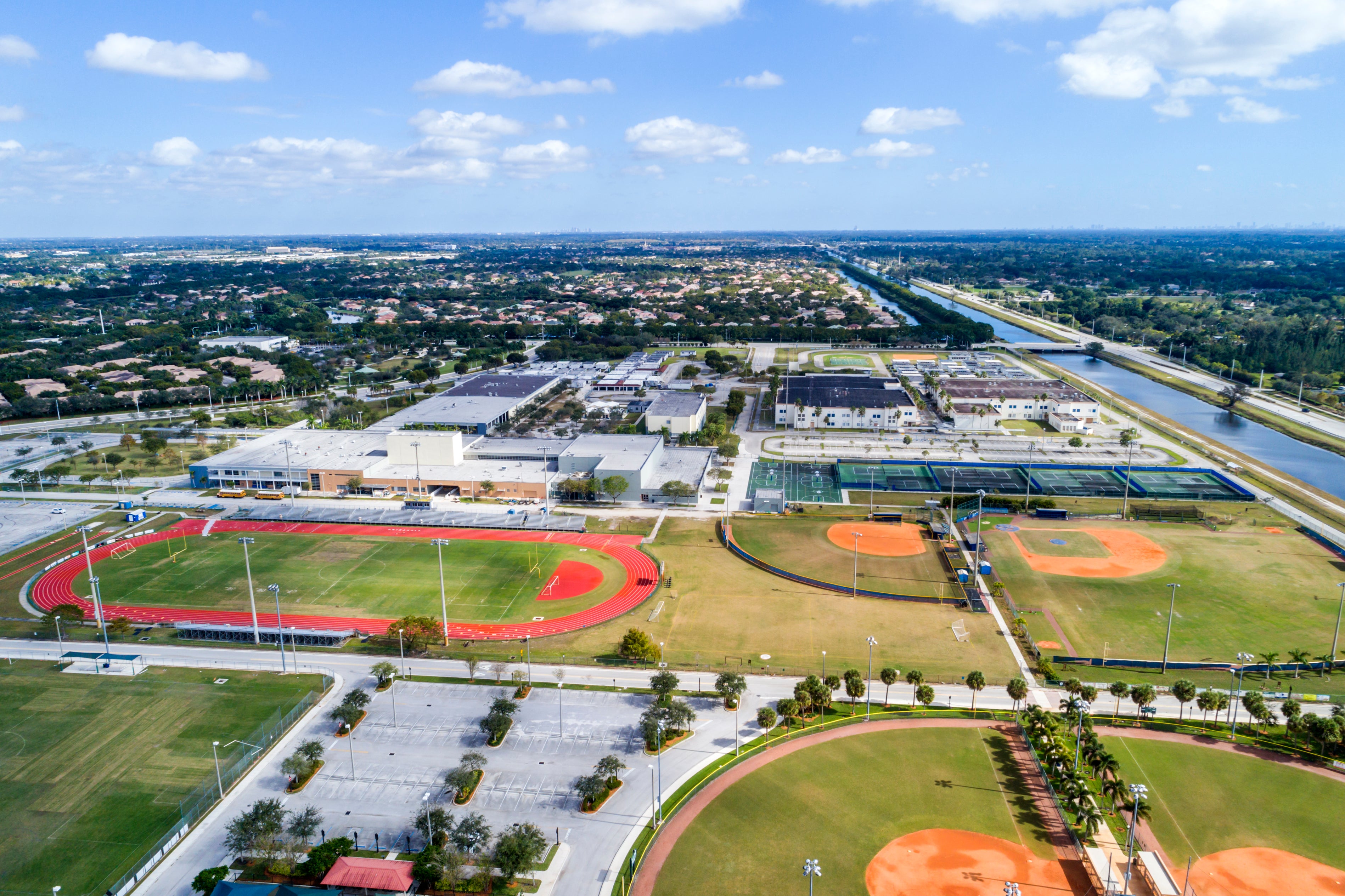 Aerial view of a large suburban high school track and baseball diamond.