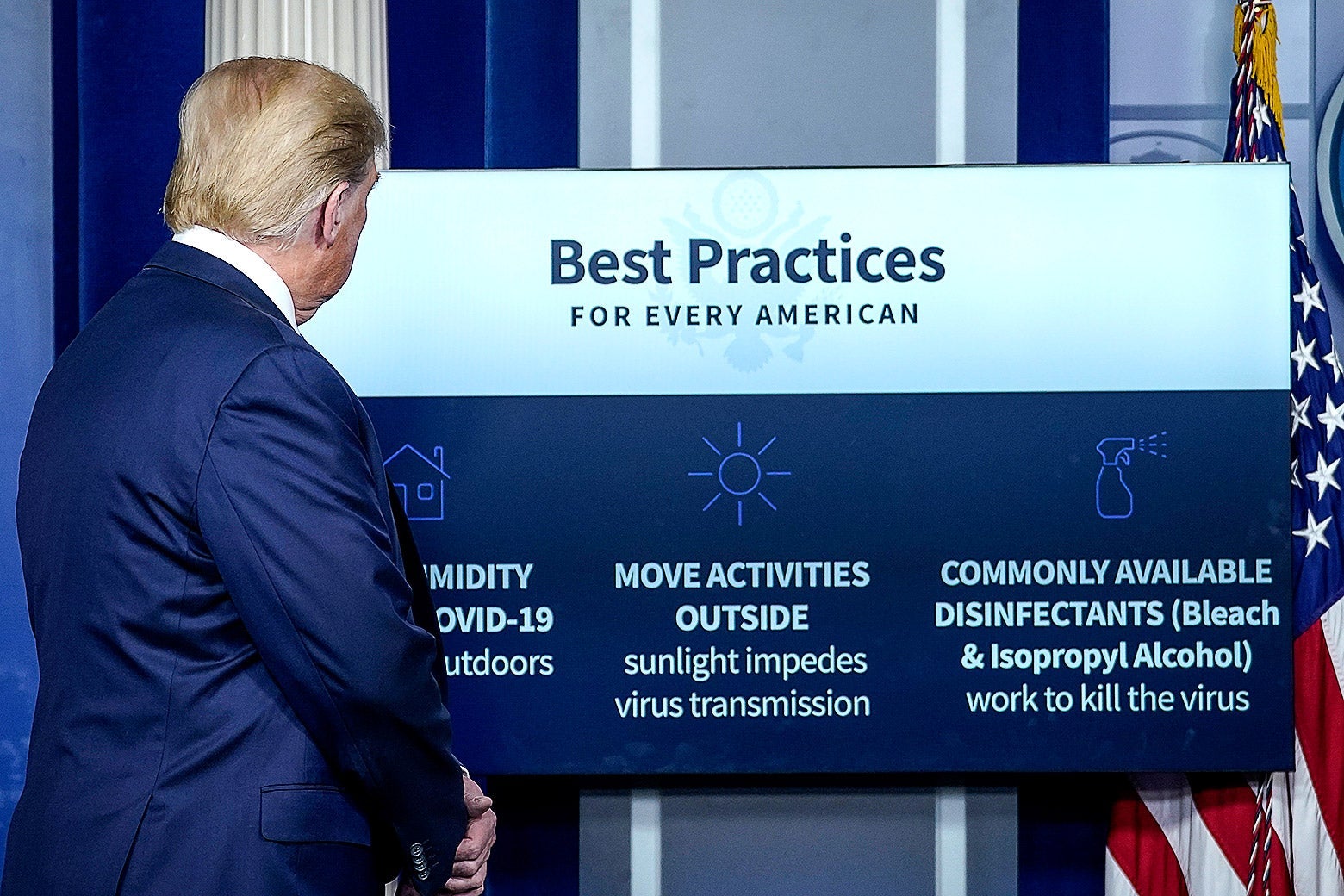 Donald Trump looks at a board behind him that says "Best Practices for Every American."