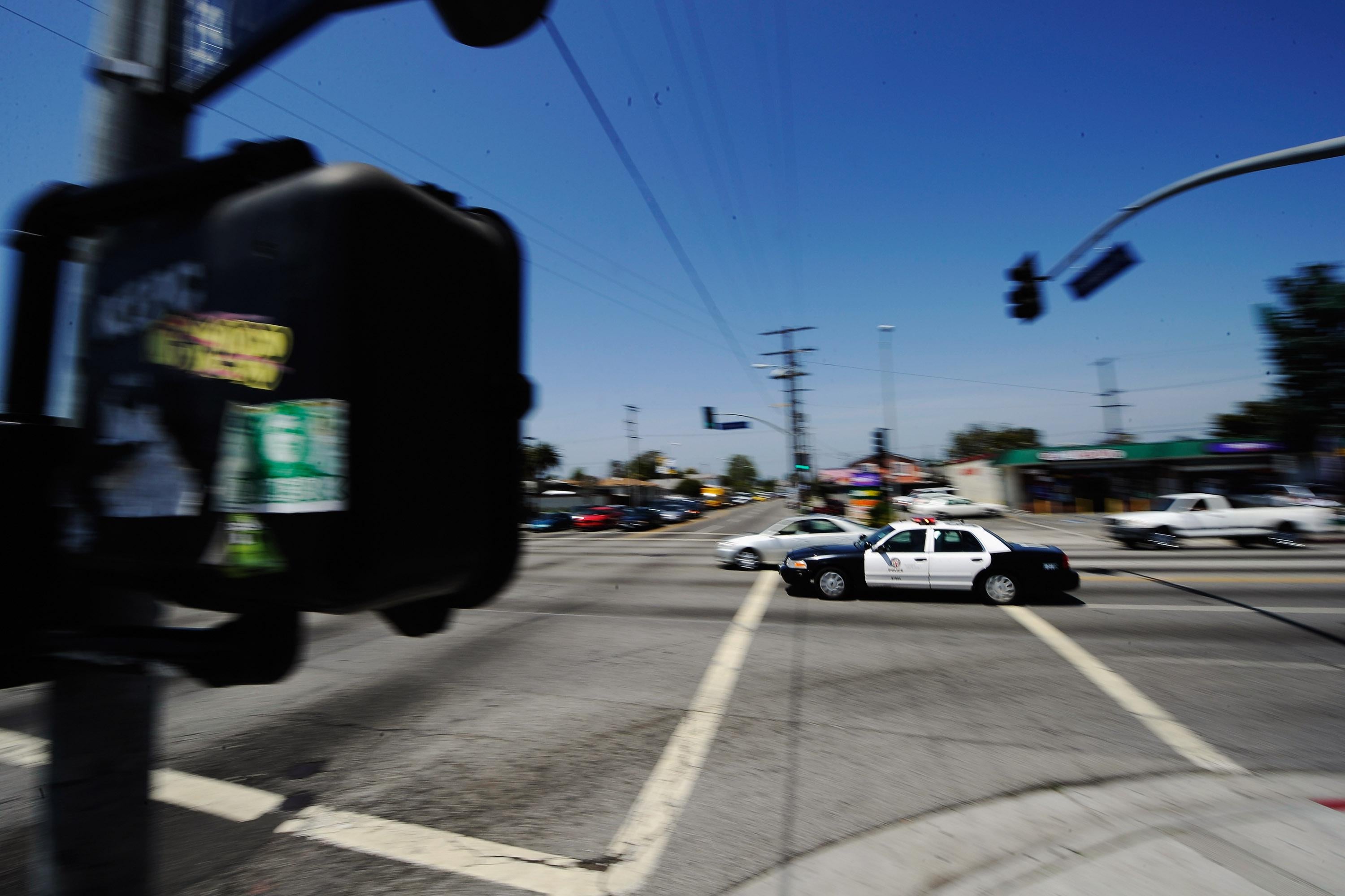 A Los Angeles Police Department car with lights and sirens going rushes through an intersection.