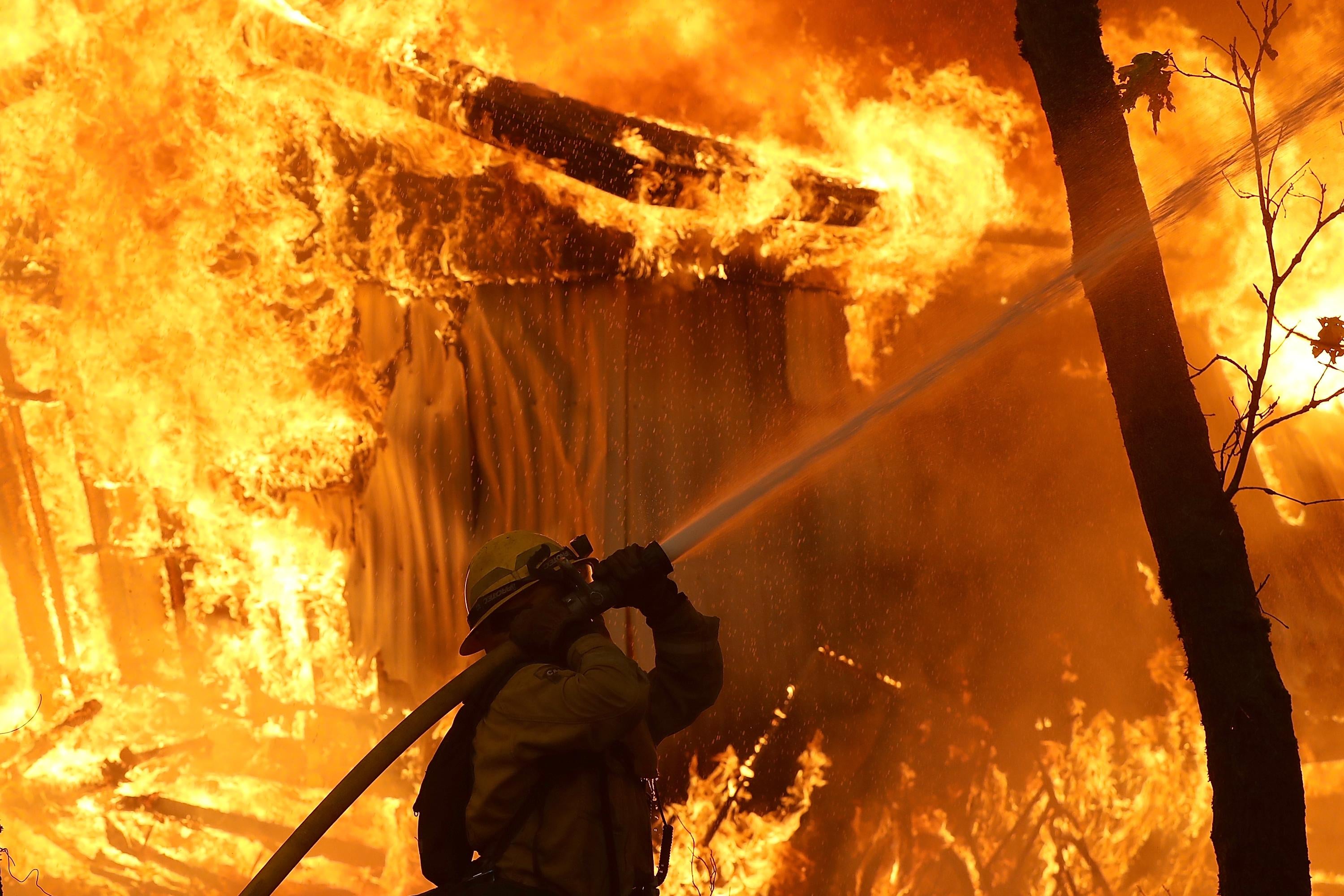 A firefighter uses a hose in the midst of a blaze.