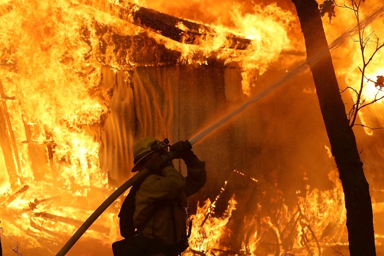 A firefighter uses a hose in the midst of a blaze.