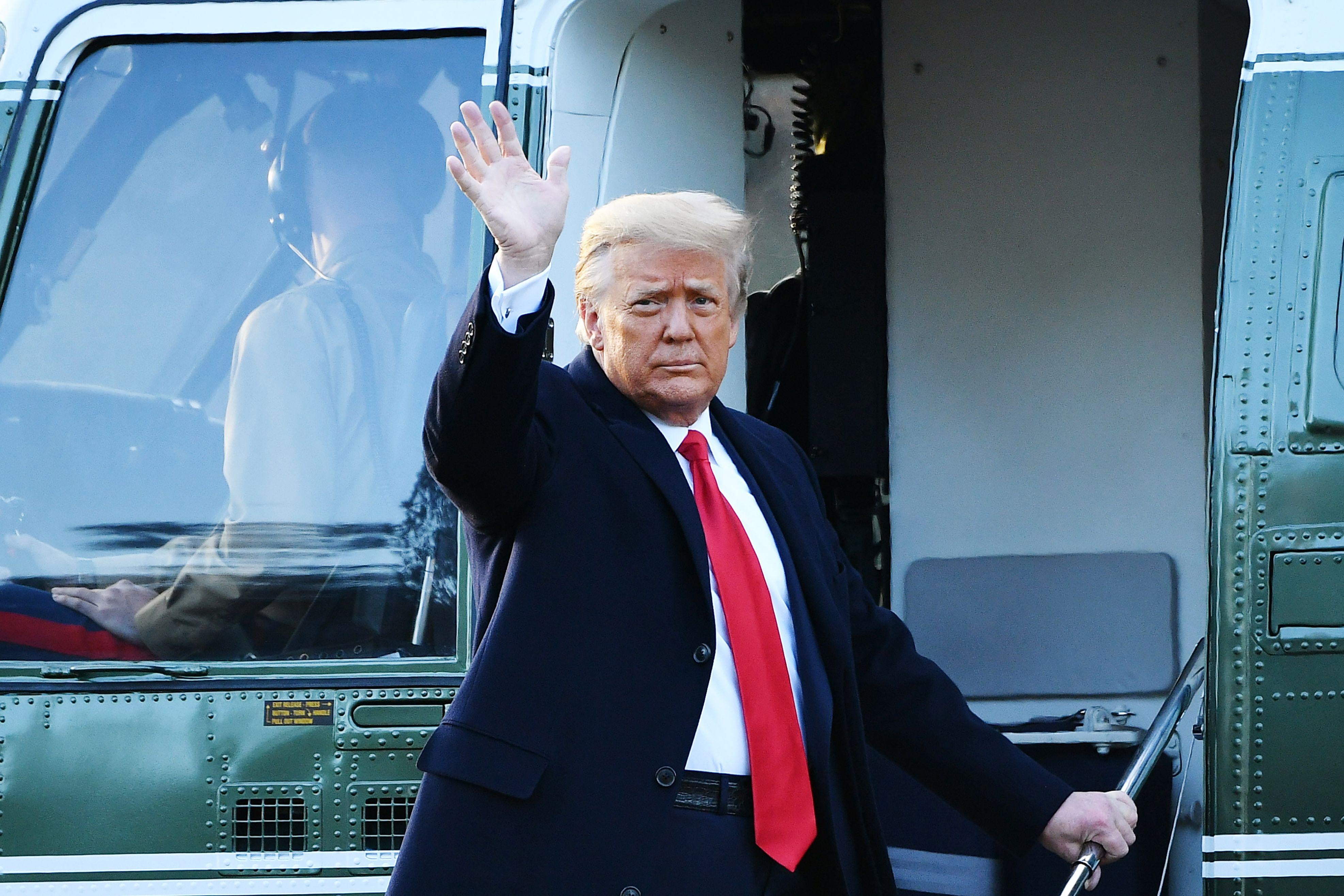 Trump waves from the stairs of a helicopter.