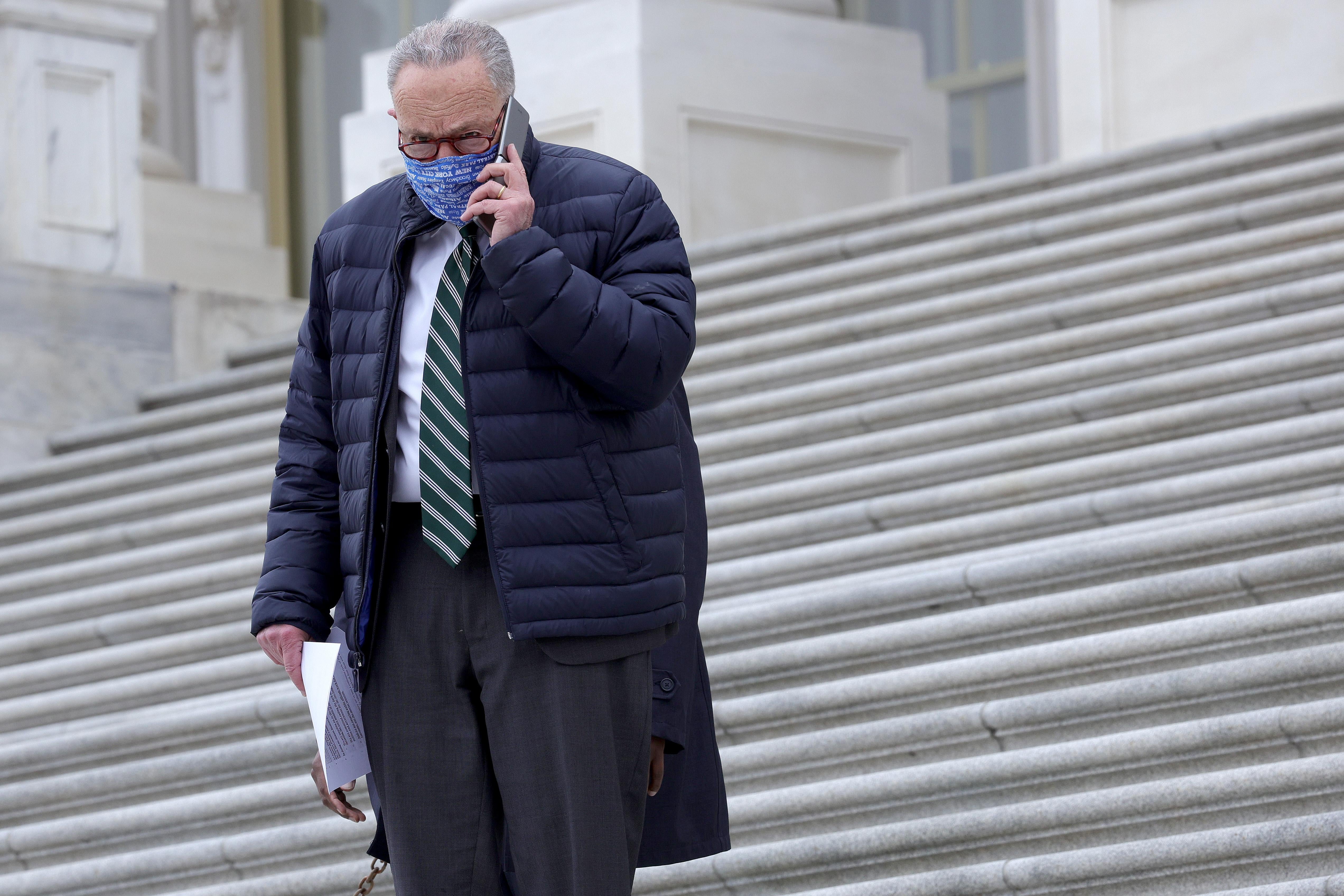 Chuck Schumer talks on his phone while walking down stairs outside the U.S. Capitol