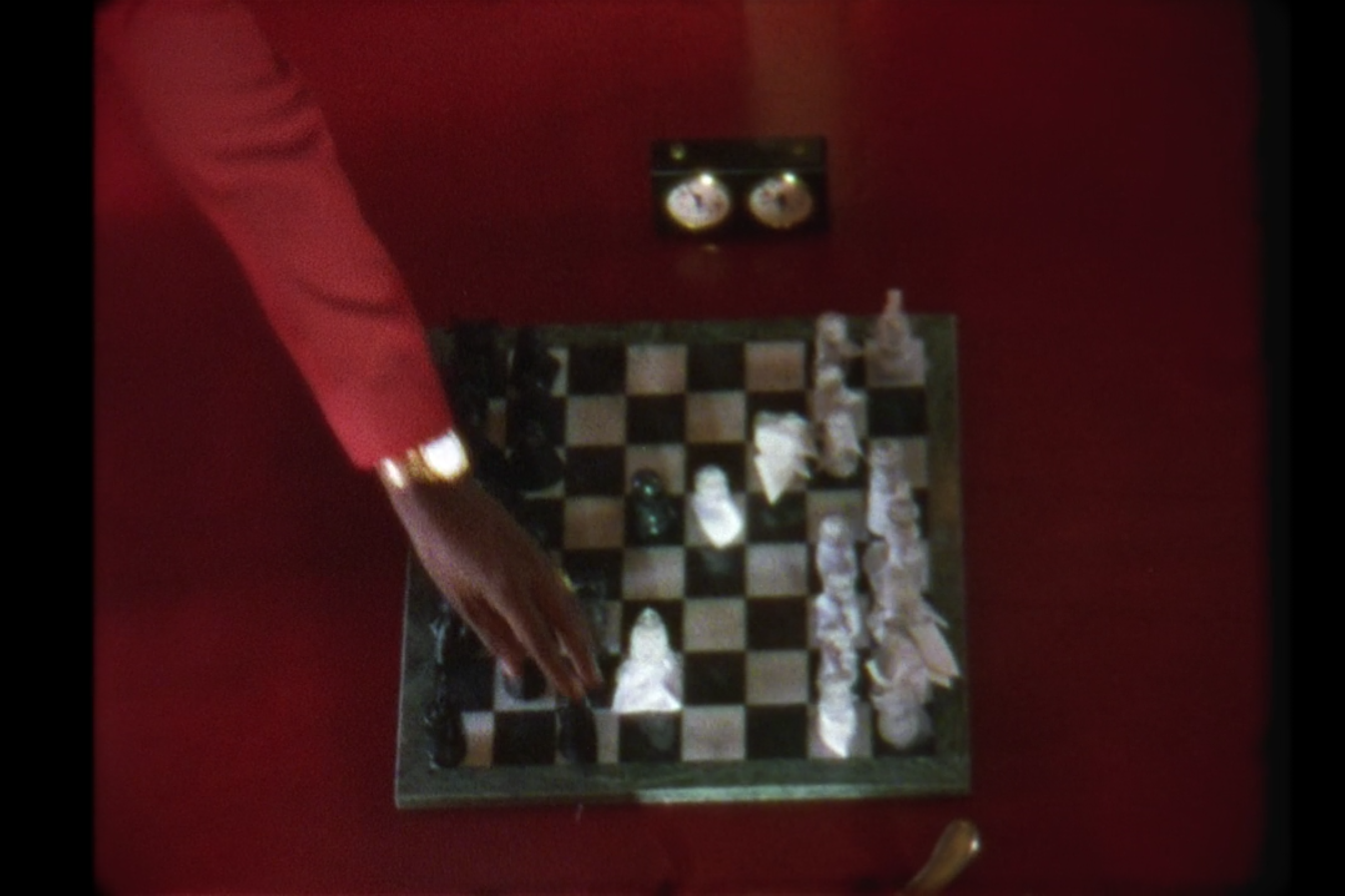 Jay-Z's hand moves a pawn on a chessboard.