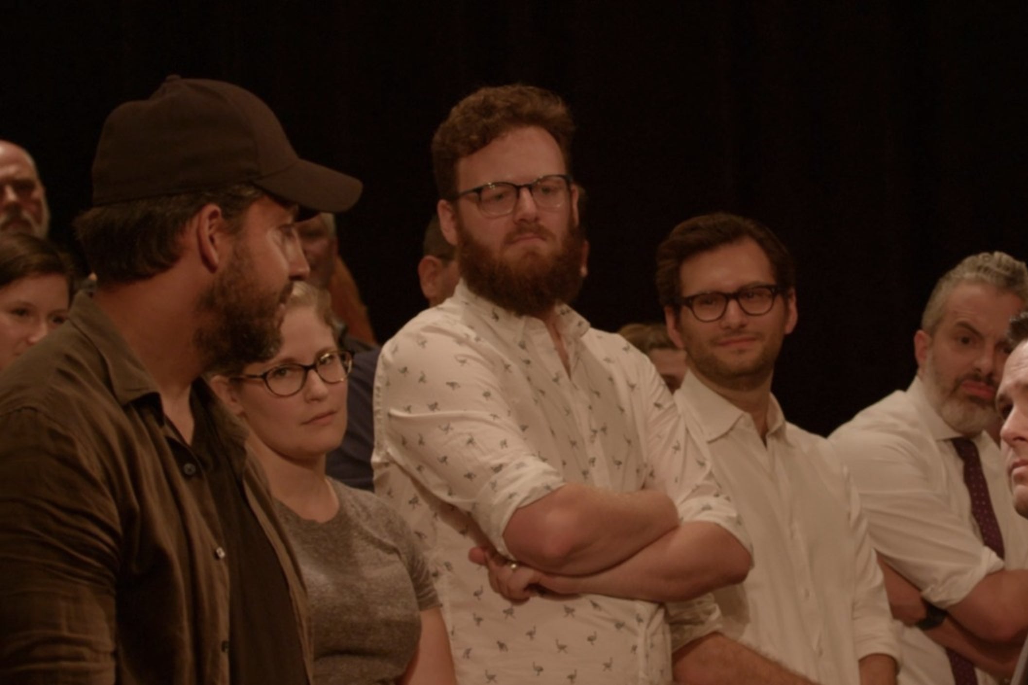 David Blaine, in a baseball hat, standing in a theatrical audience. 