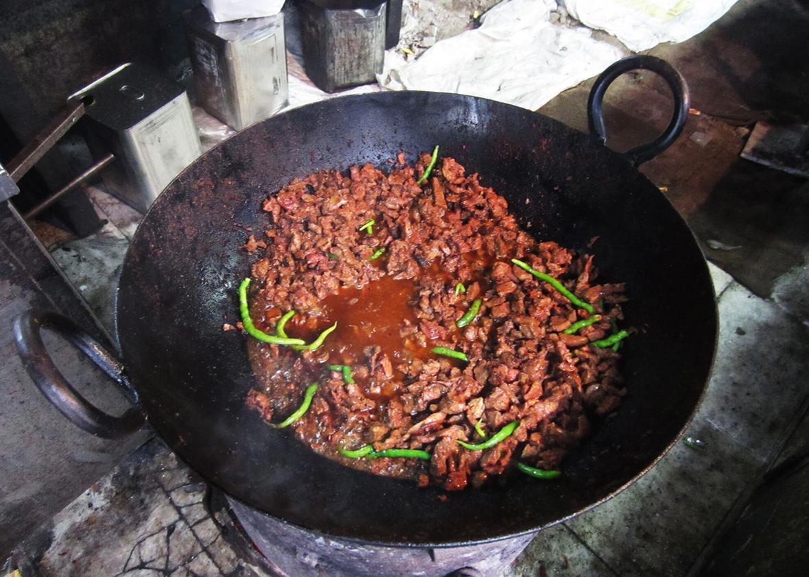 A dish of tallava gosht slow frying in peanut oil on a cast-iron tava at the entrance to Al-Hamdullillah.