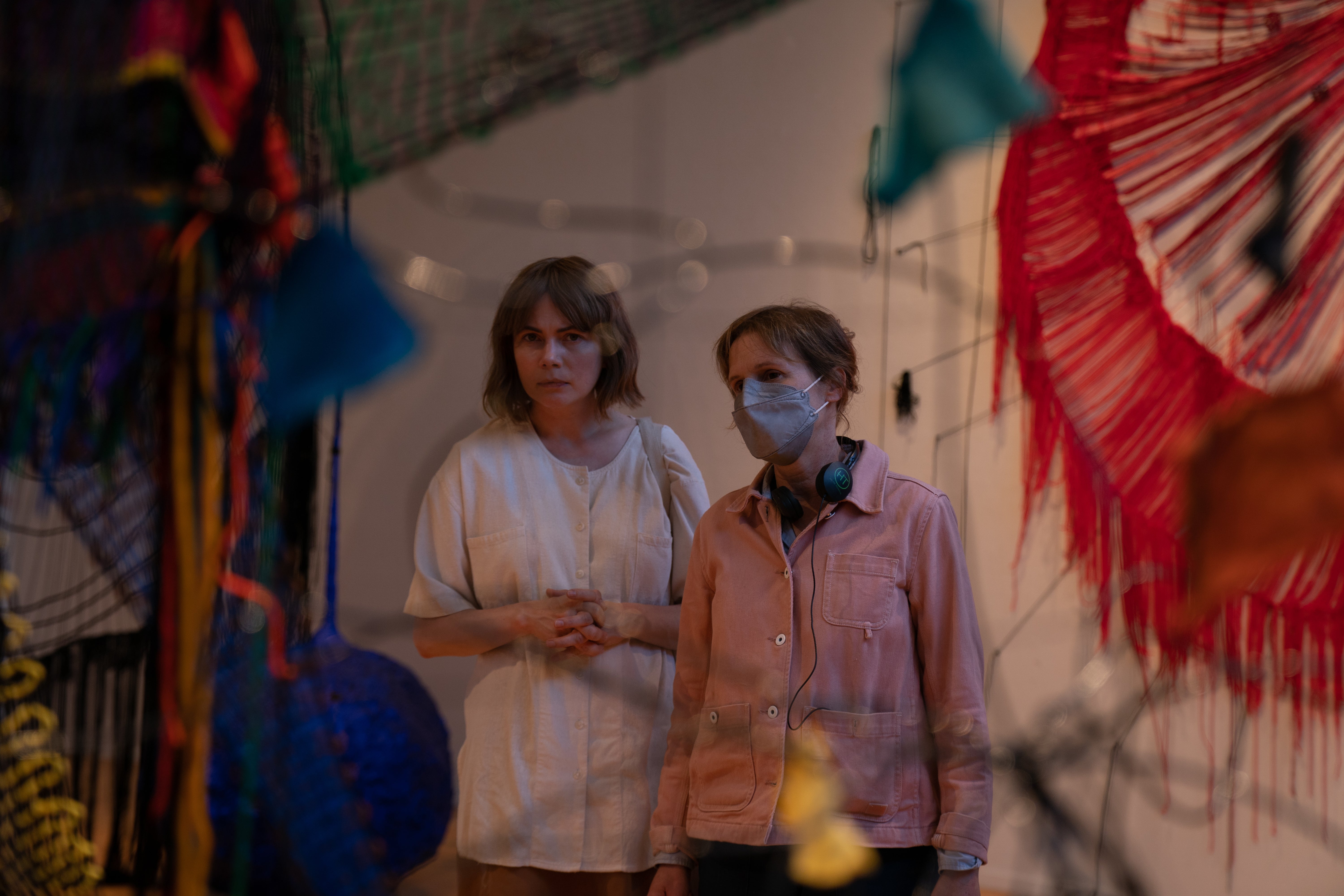 The actress Michelle Williams stands next to the director Kelly Reichardt in a gallery space filled with contemporary fabric sculpture.