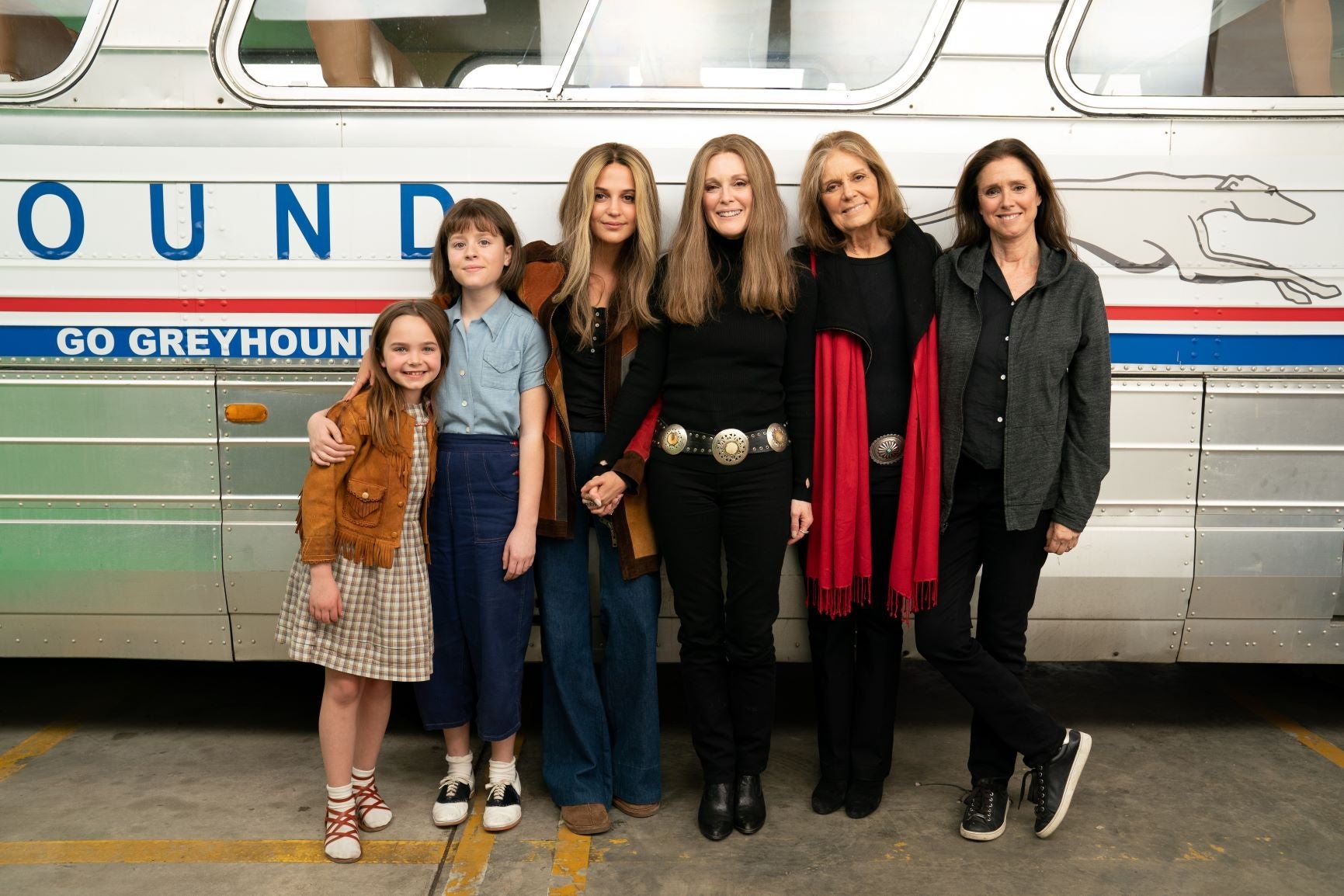 The six women stand in front of a Greyhound bus, many of them with long brown hair parted down the middle like Steinem’s