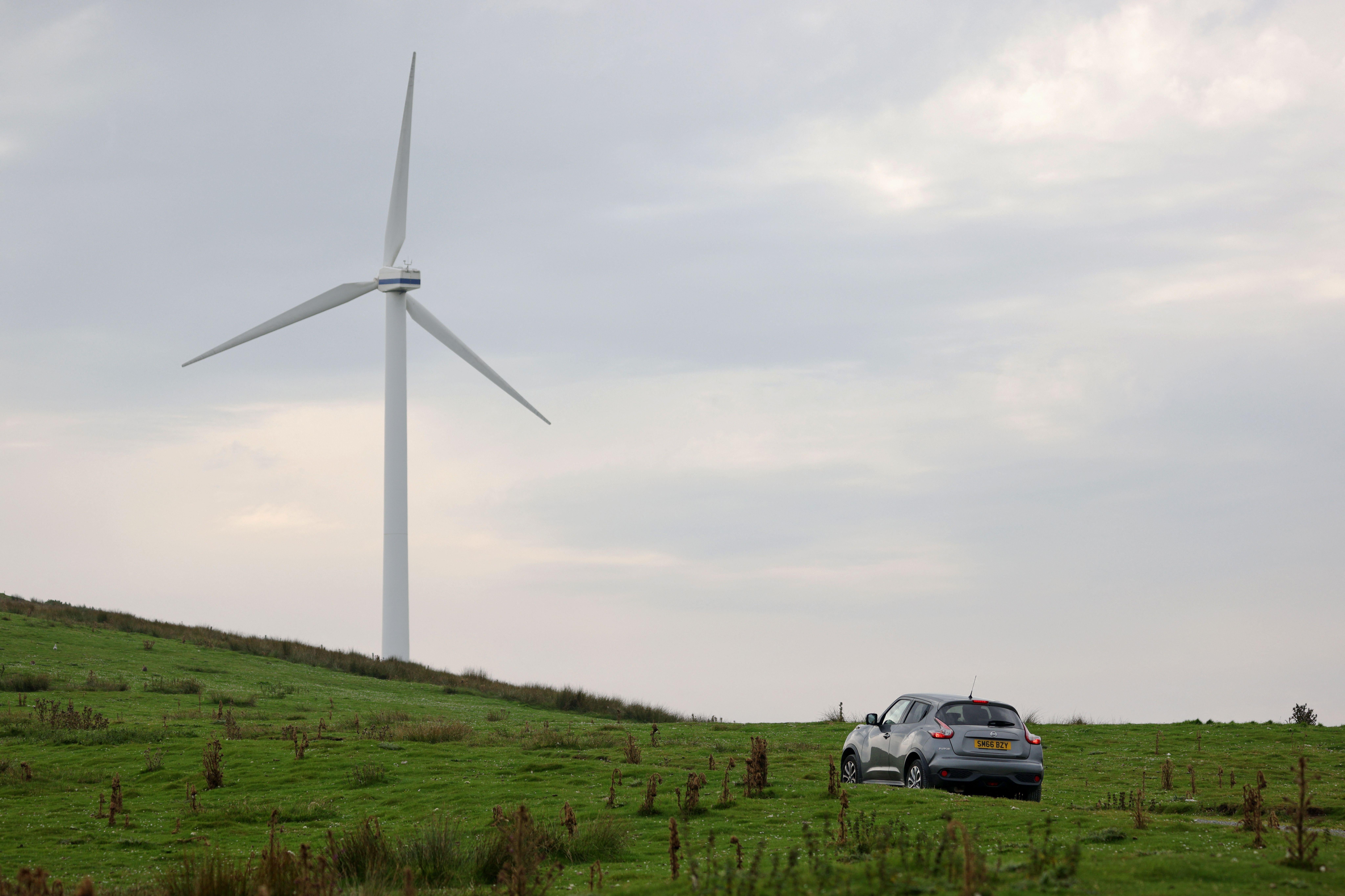 A car near a wind turbine.