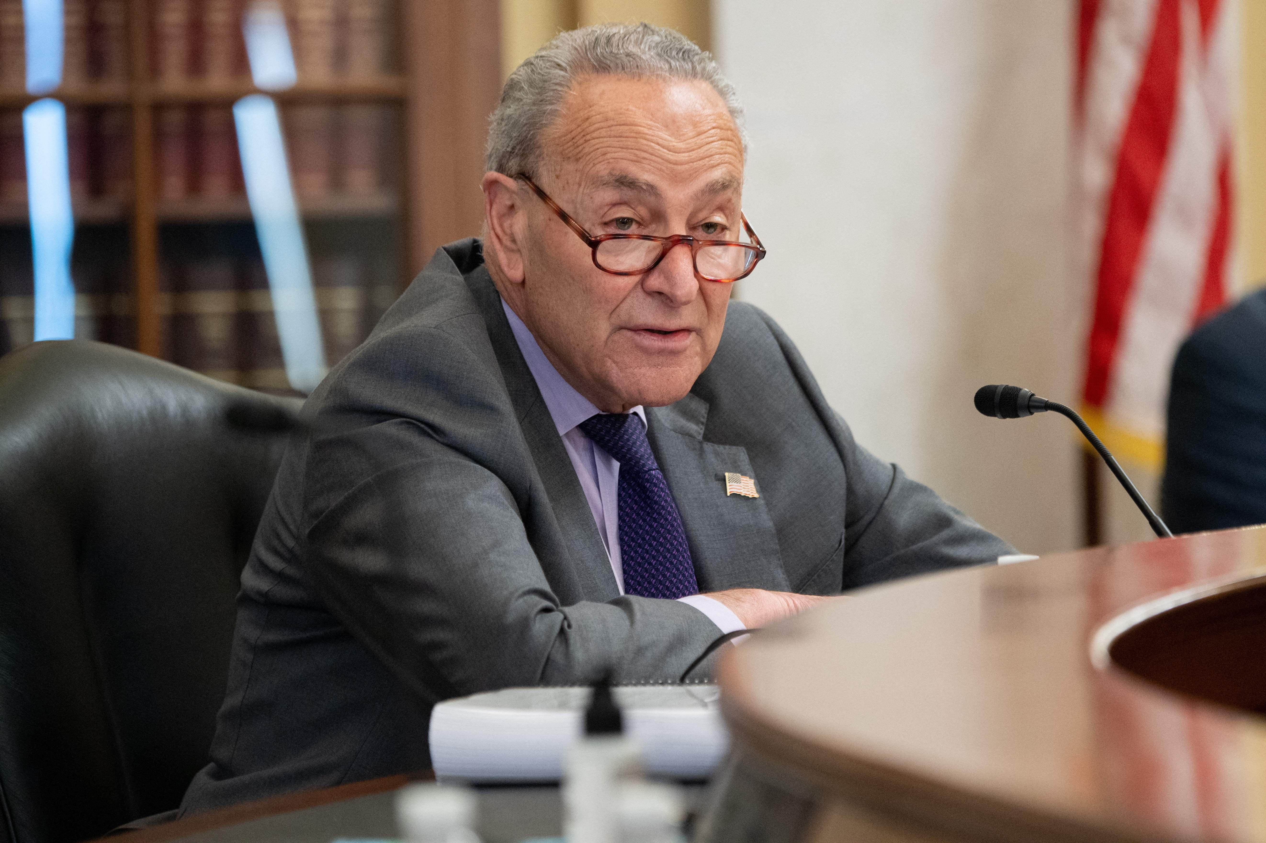 Schumer sits at a desk with a mic in front of him