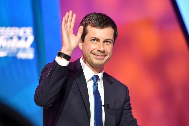 Buttigieg raising his hand and smiling onstage.