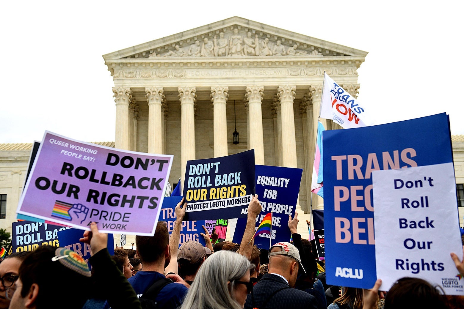 LGBTQ rights activists protest outside the Supreme Court, holding signs that say "Don't Roll Back Our Rights."