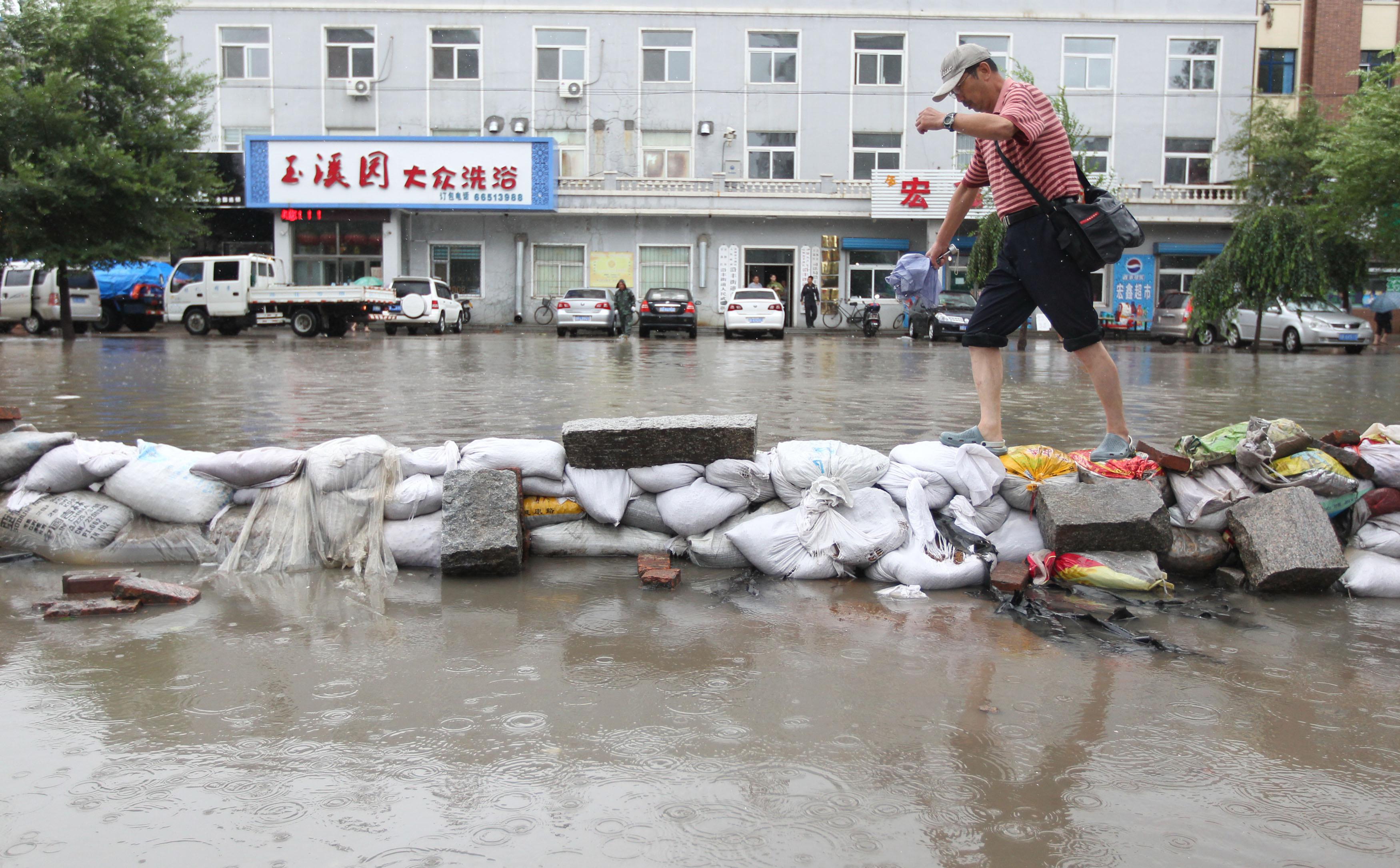 This picture taken in August shows a man walking over pooling water in the heavy rain brought by typhoon Bolaven in Jilin, northeast China's Jilin province. 