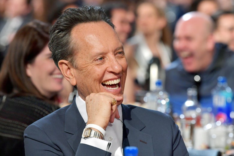Richard E. Grant sitting at the Independent Spirit Awards, laughing.
