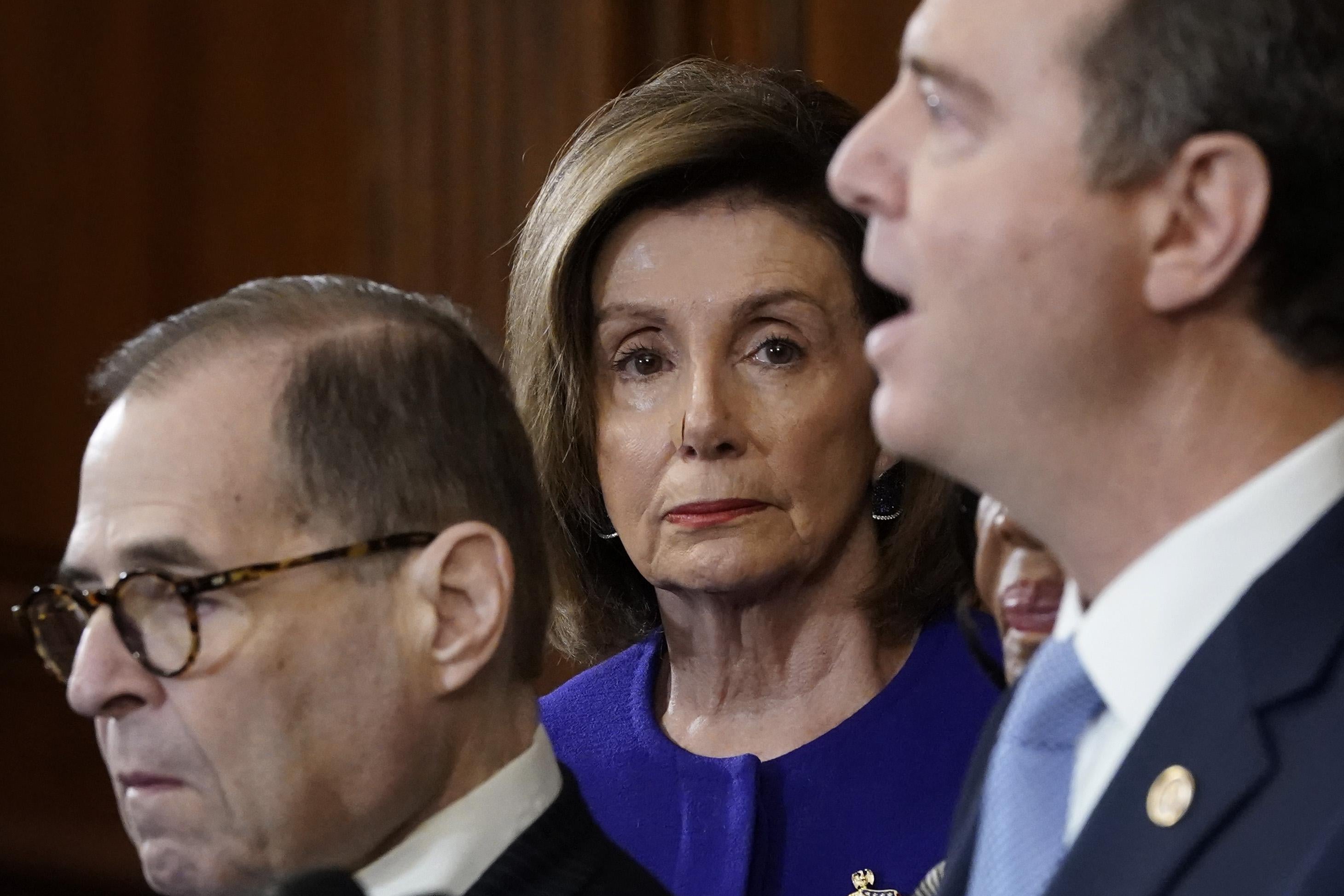 Nancy Pelosi stares directly at the camera as Jerry Nadler stares off in the distance and Adam Schiff speaks into the mic.
