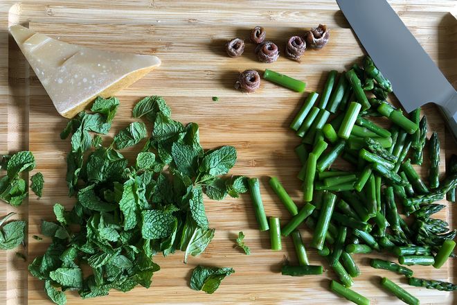 Chopped asparagus and mint on a cutting board.