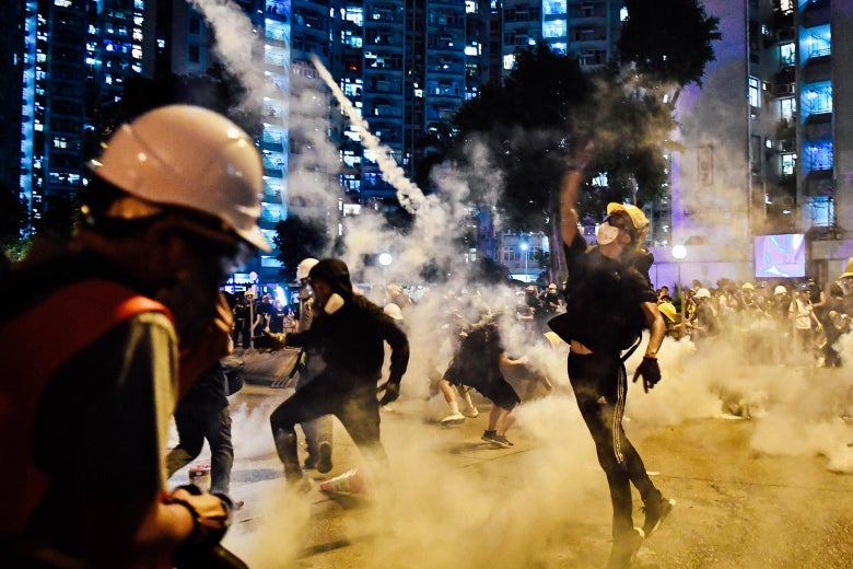 Protesters throw back tear gas fired by the police during a general strike in Hong Kong.