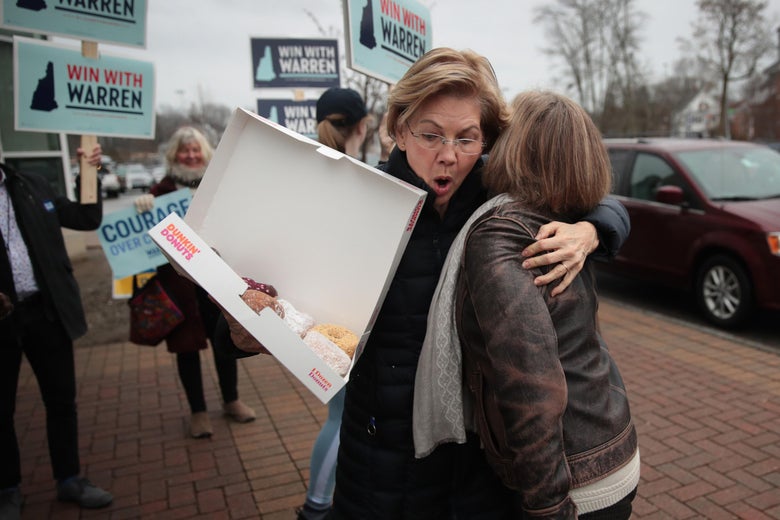 Sen. Elizabeth Warren almost drops a box of doughnuts as she gets a hug from a supporter