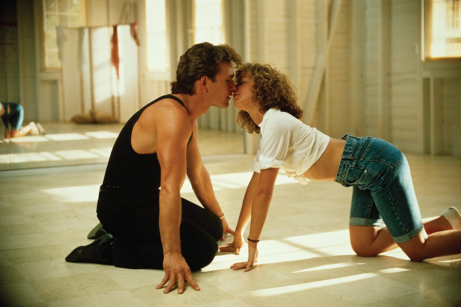 Jennifer Grey and Patrick Swayze almost kissing on the floor of a dance studio.