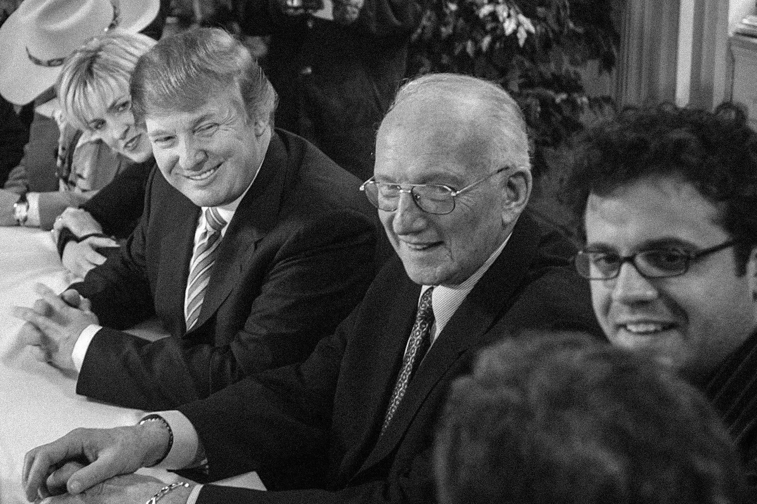 Kepcher, Trump, Ross, and LaPlante smile around a table while talking to a contestant.