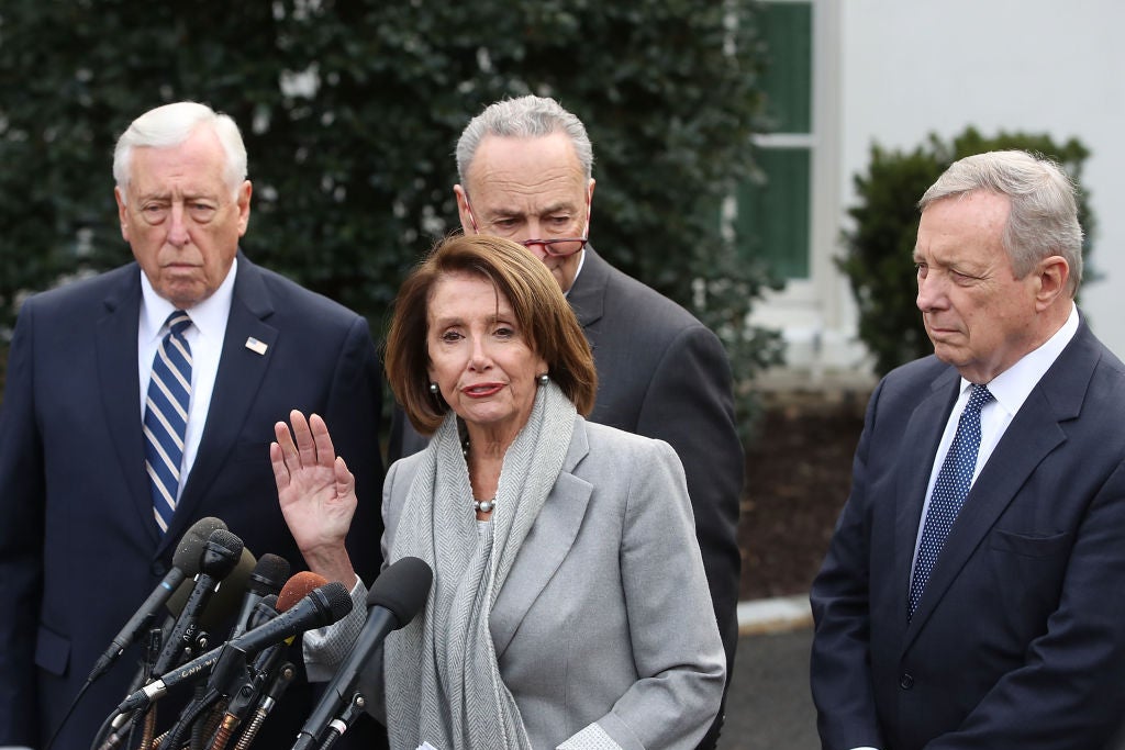 Pelosi speaks as the three men watch her in what appears to be a White House driveway.