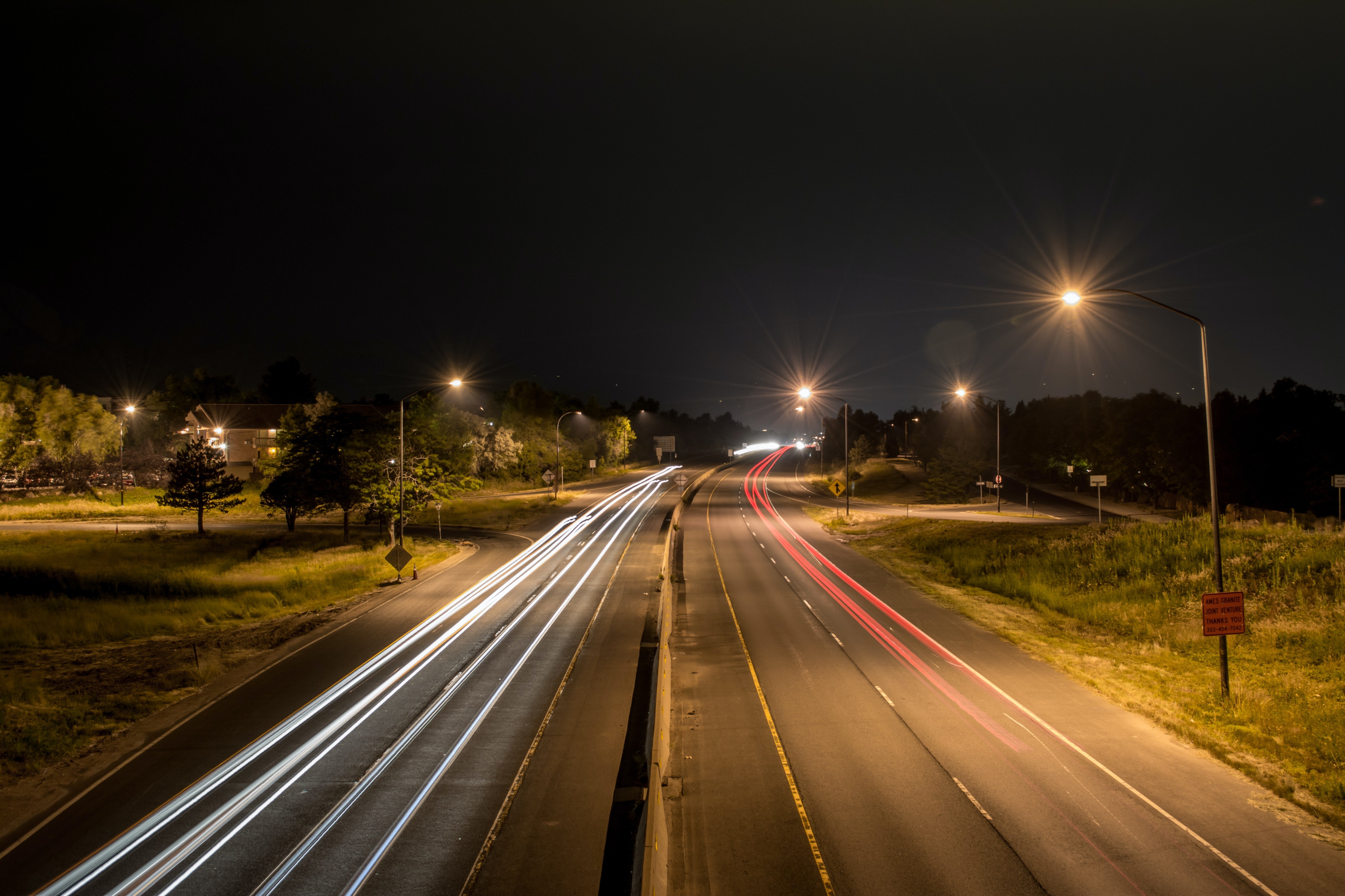 Cars driving across a large road at night.