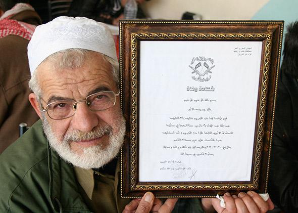 Abu Yaseen holding his son's martyrdom certificate.