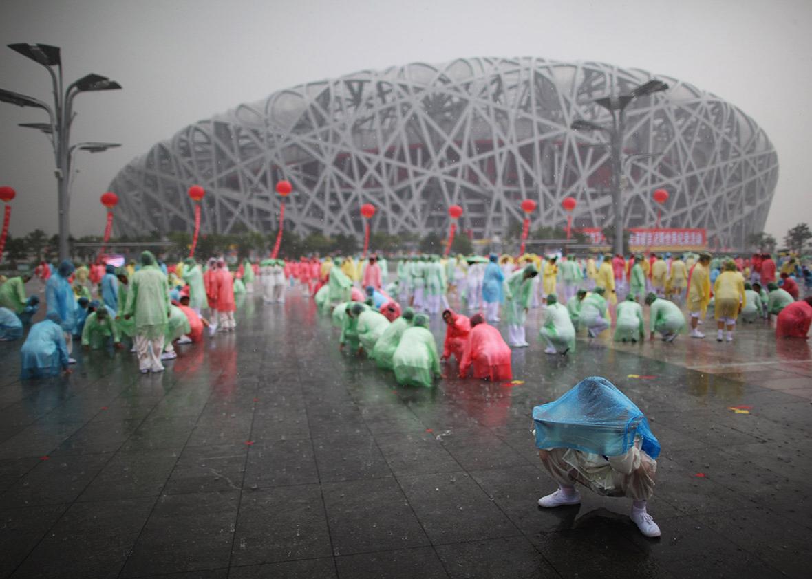 People prepare to perform tai chi in the rain outside the 2008 Olympic stadium, known as the Bird’s Nest, on Aug. 8, 2009, in Beijing.