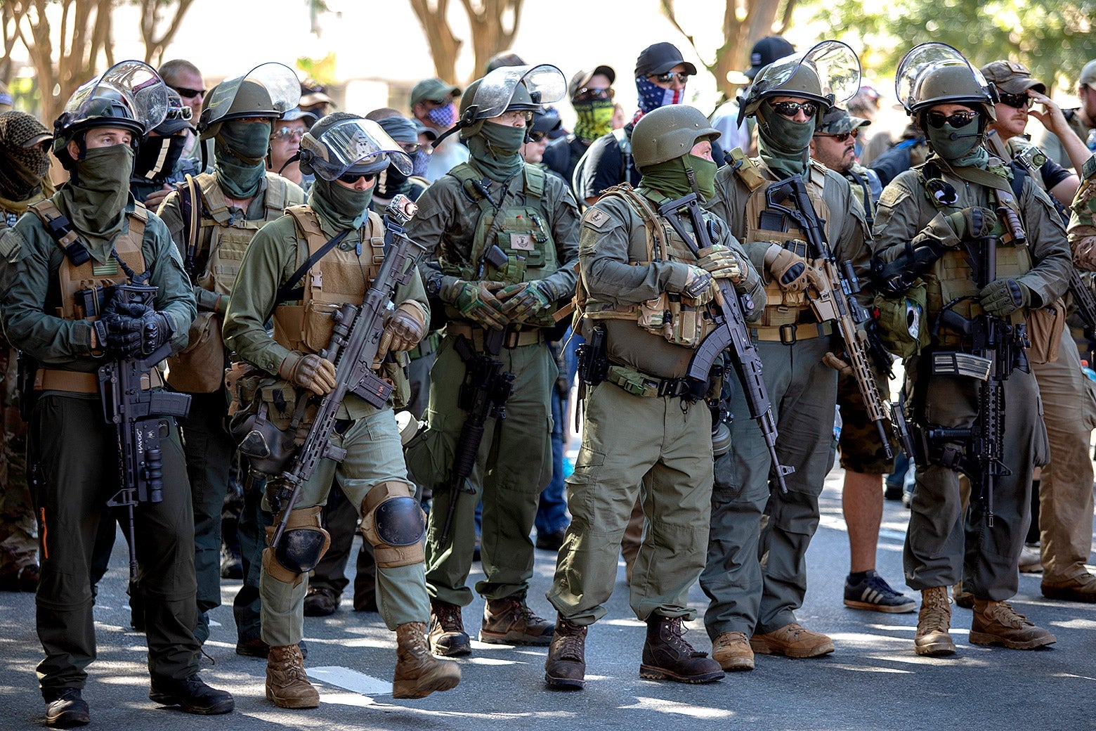 A group of men in camouflage tactical gear carry large rifles.