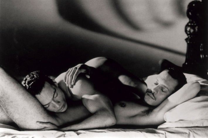 Two naked men embrace on a bed in a black-and-white still from Looking for Langston.