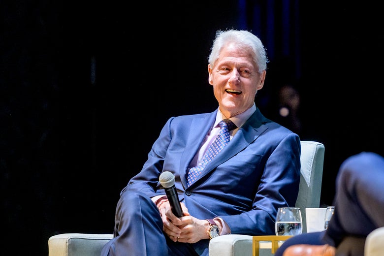 Bill Clinton sits onstage for an event.