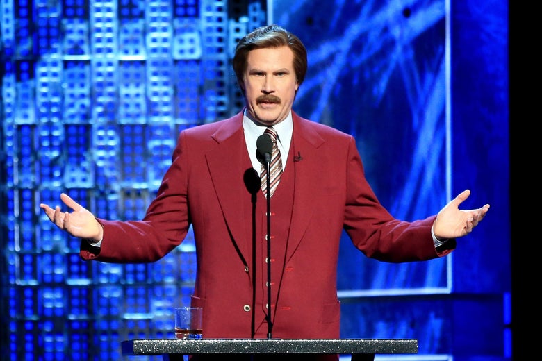 Will Ferrell stands at a podium, arms raised, wearing his Ron Burgundy red suit and mustache.