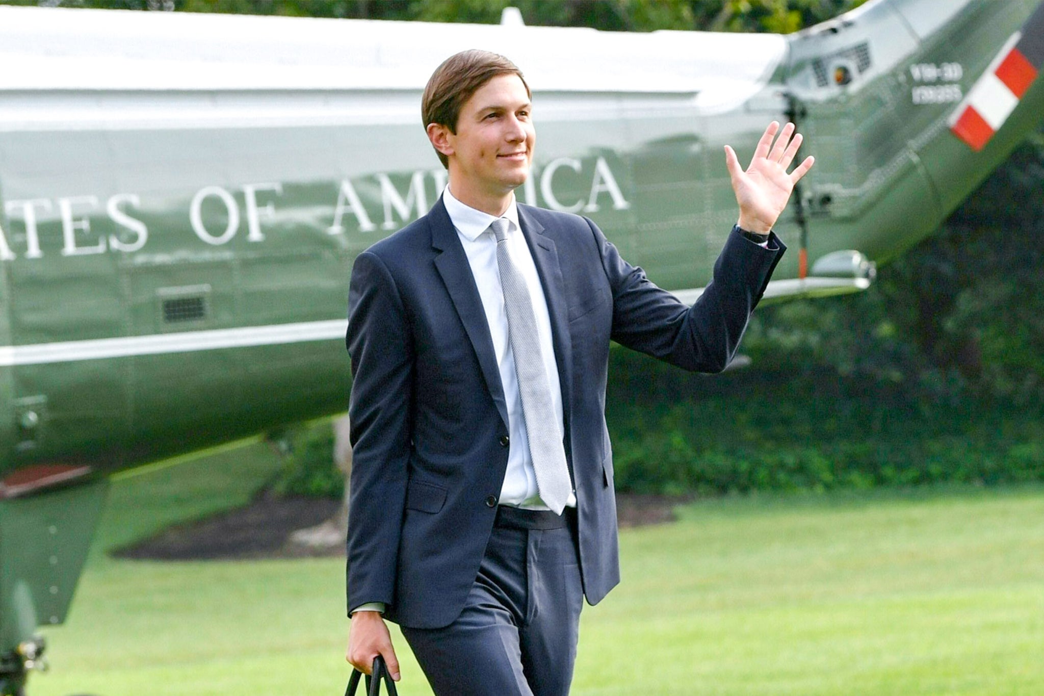 A photo shows Kushner striding across the White House lawn after getting off a helicopter painted with the words "United States of America." He waves, wearing a slim suit, dimples on his cheeks.