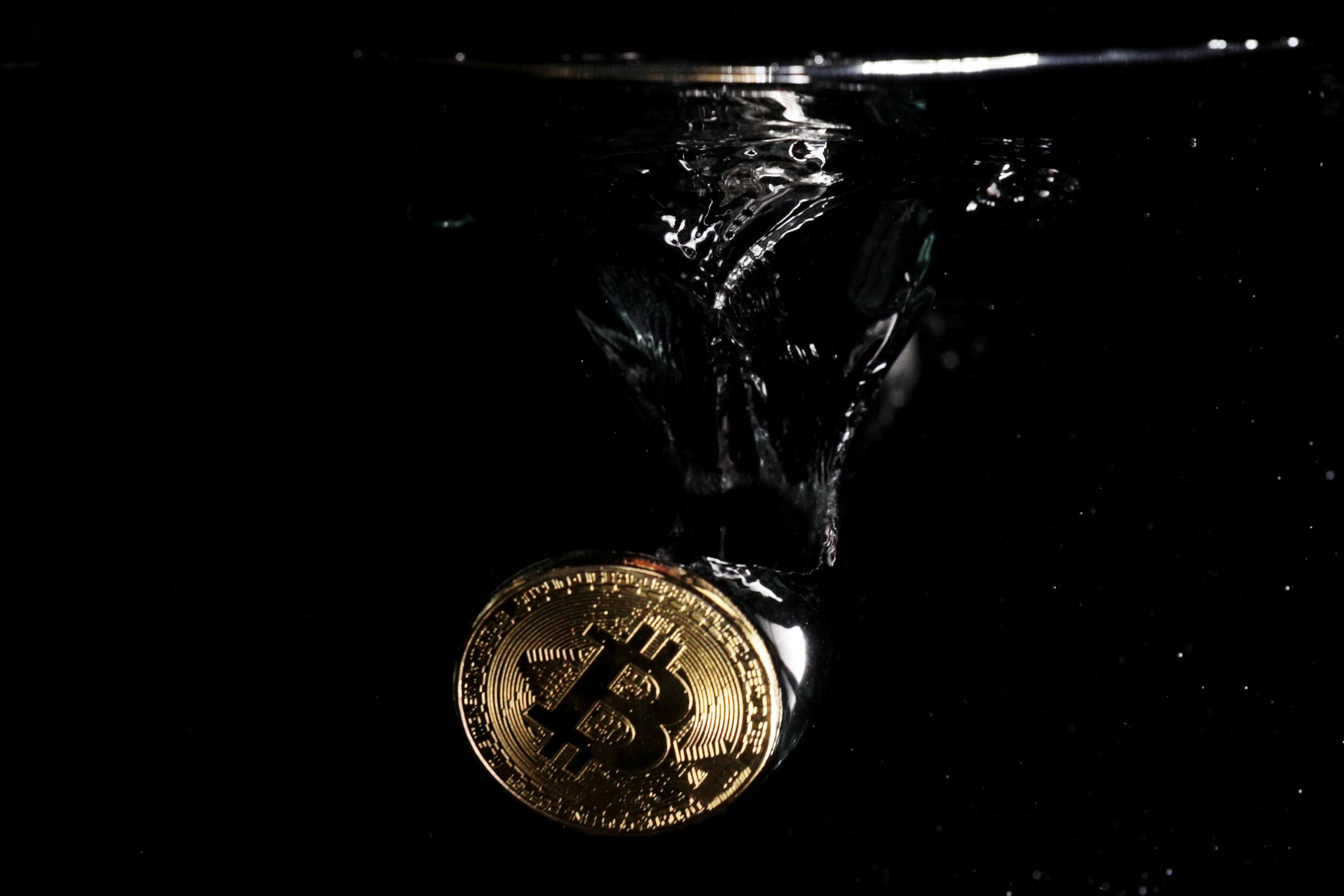 A bitcoin symbol submerged in water.